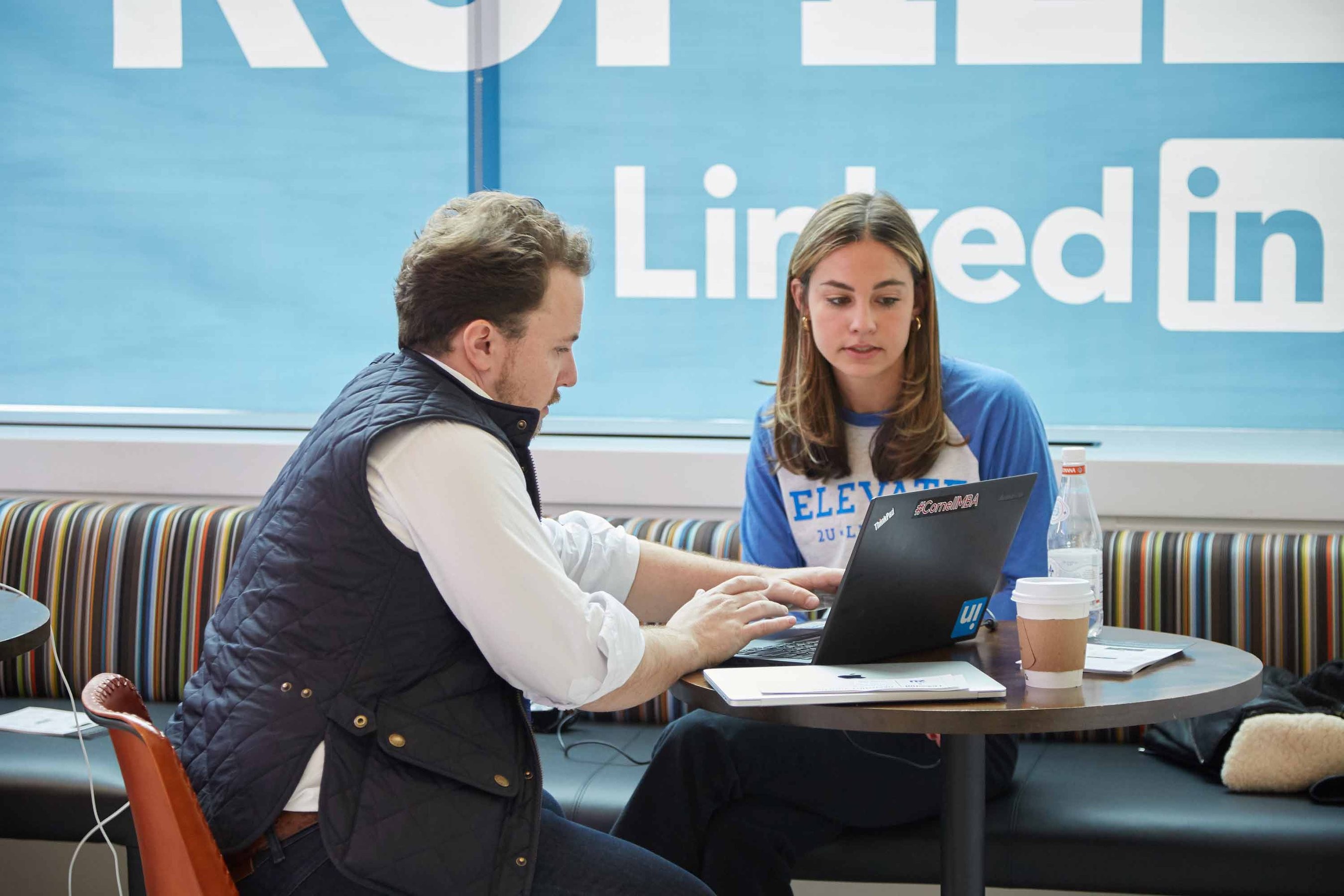 2U and LinkedIn colleagues work on a laptop in a break area"