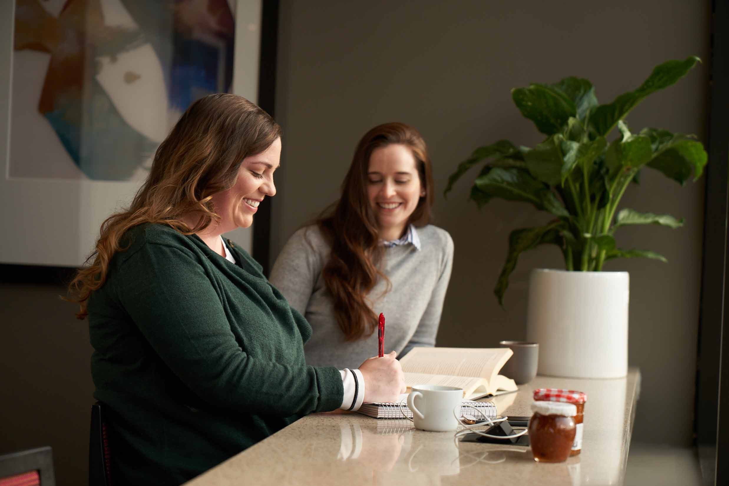 Two MIT students laugh and have coffee while they study