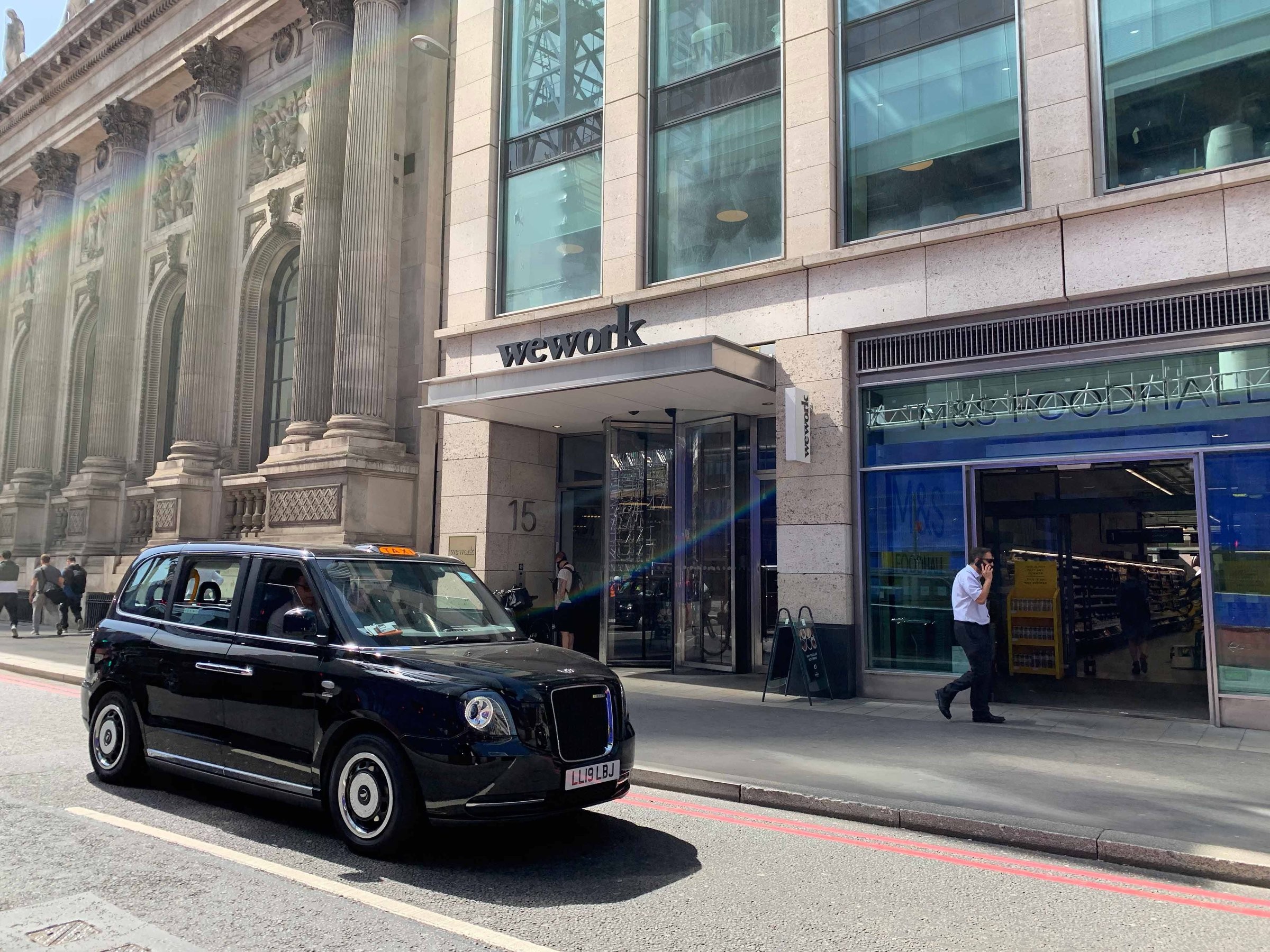 A british taxi parked in front of the WeWork office in London