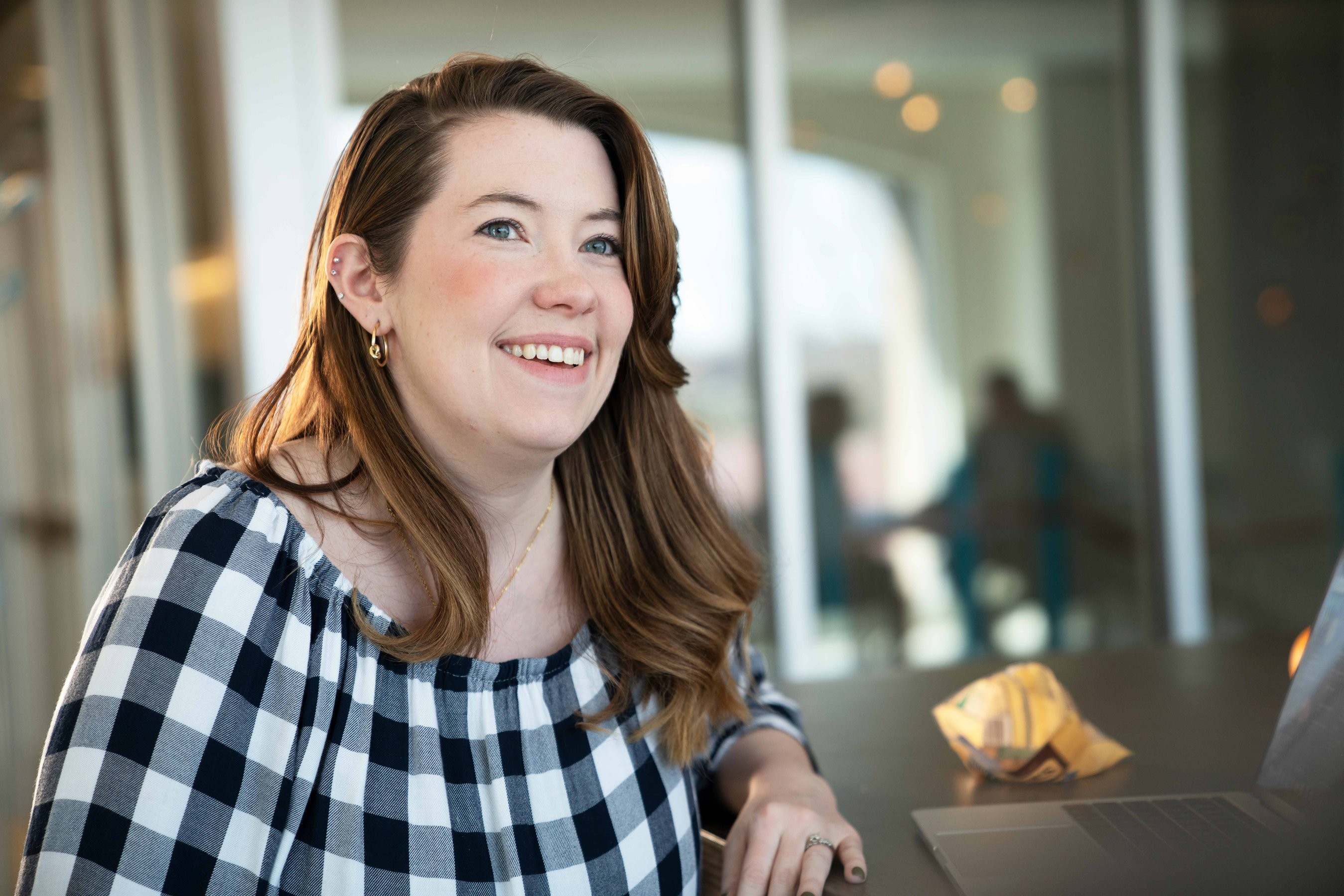 Woman in black and white checkered dress smiles in an office