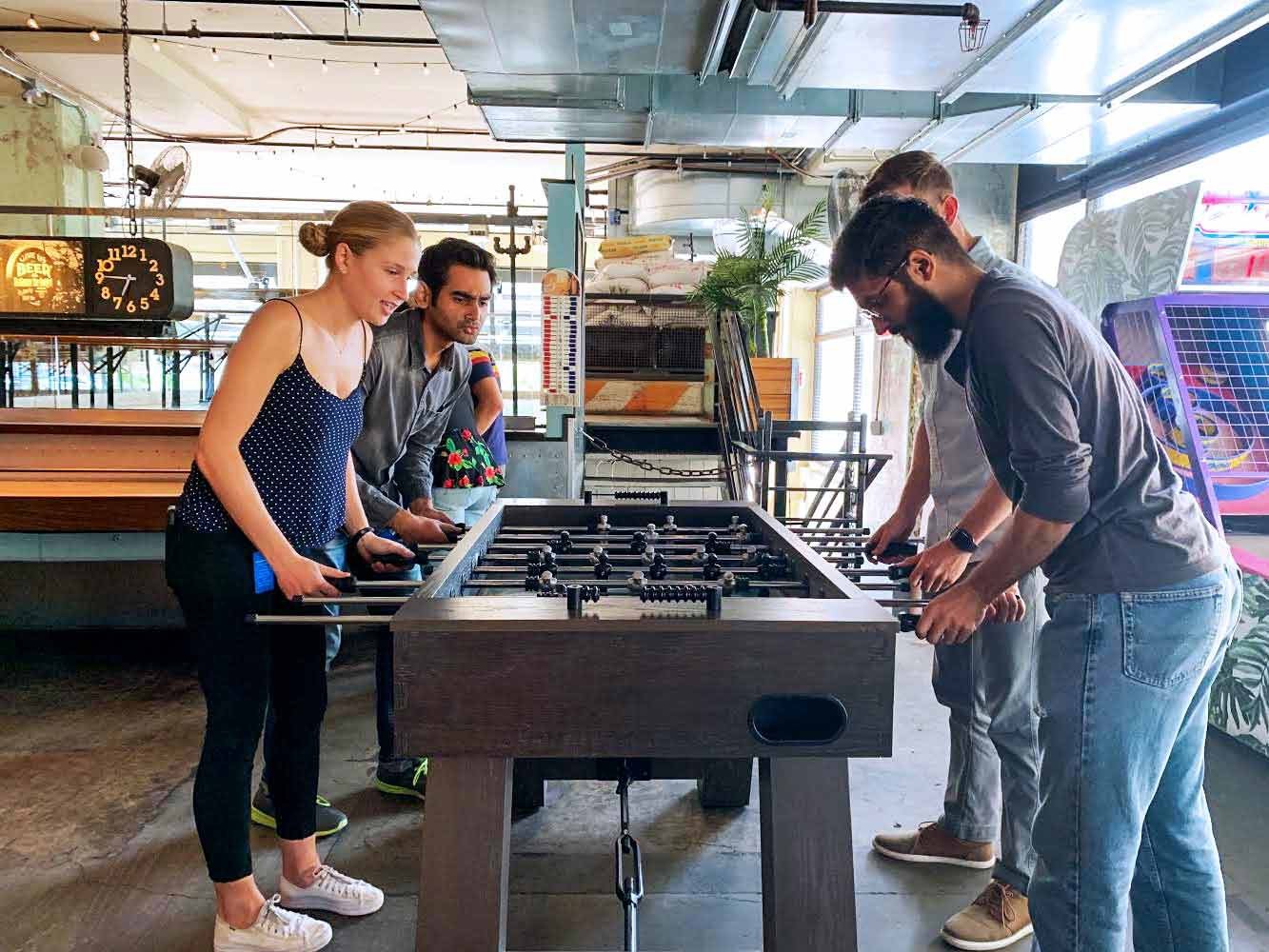 A group of interns unwind after work with a game of foosball