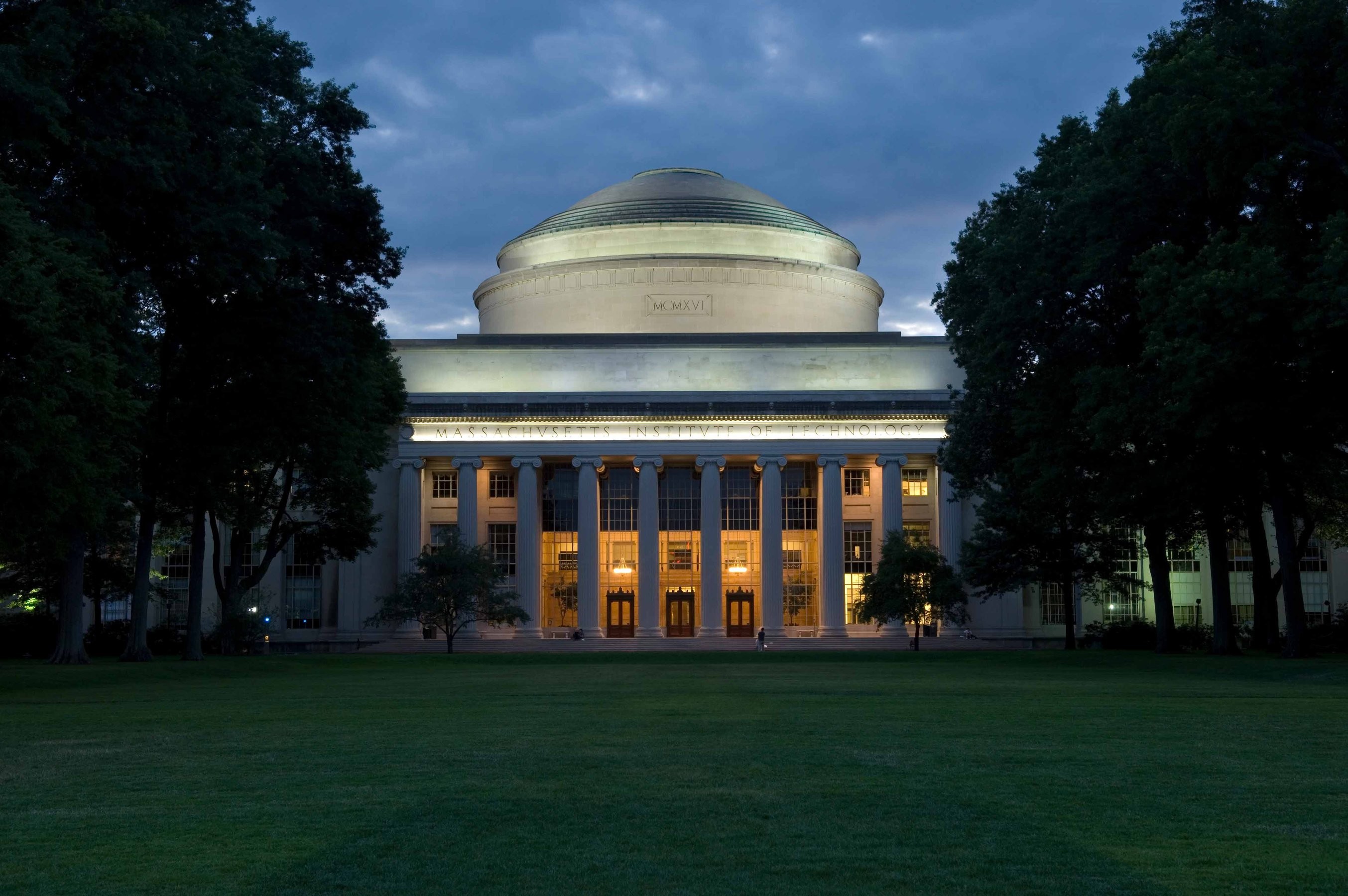 Trees and a grassy quad line the entrance to the Great Dome at MIT