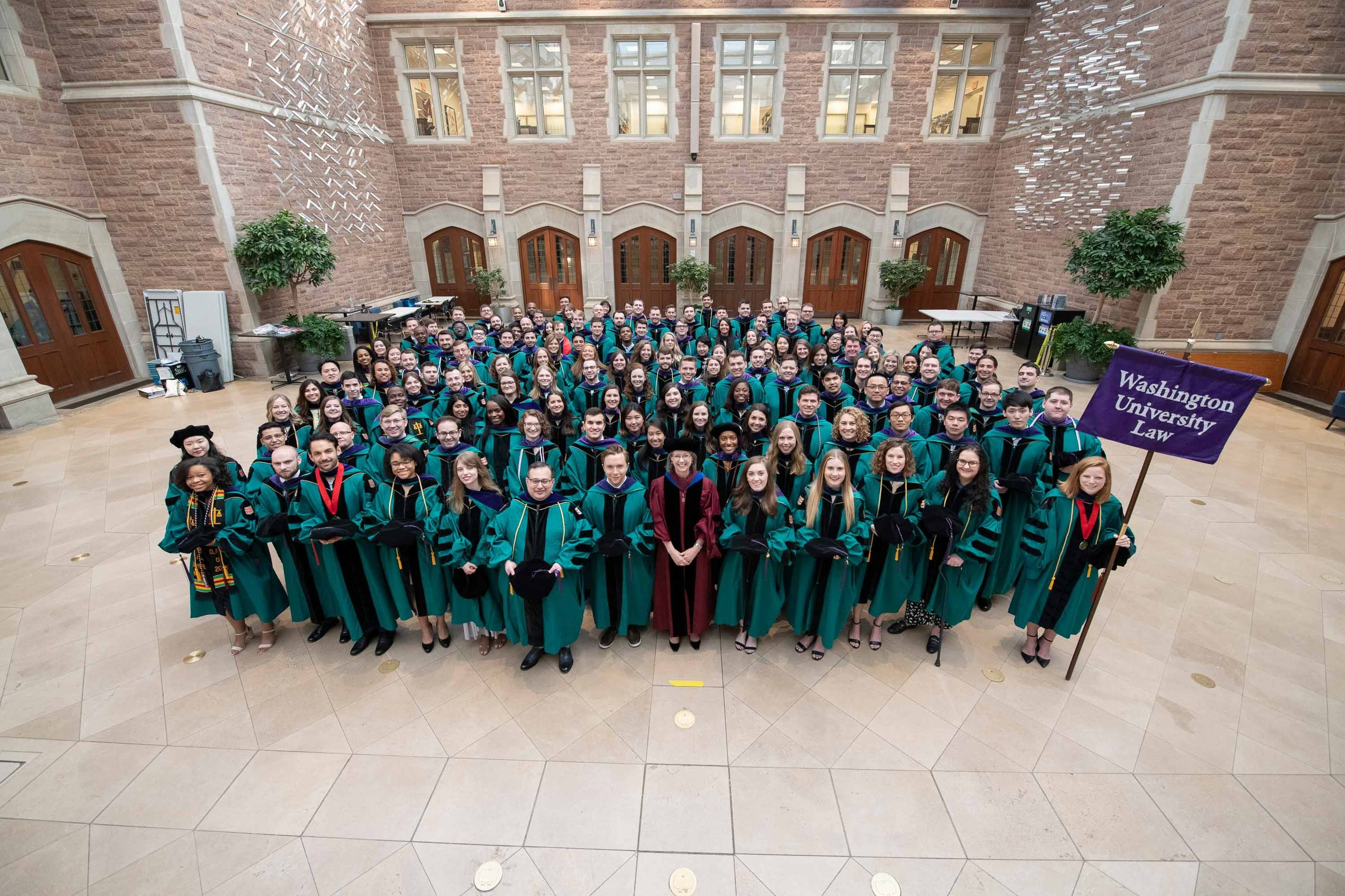 Washington University in St. Louis Law school graduates take a group photo in caps and gowns outside Anheuser-Busch Hall